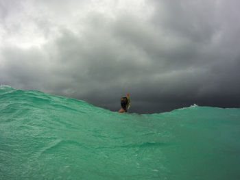 Woman snorkeling in sea against storm clouds