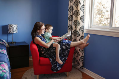 Mother with son boy sitting  at home and reading book. child kid early development education