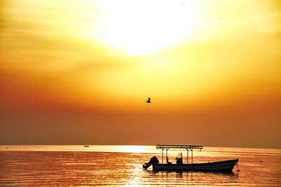 Silhouette boat in sea against sky during sunset