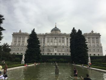 People in front of historical building against cloudy sky