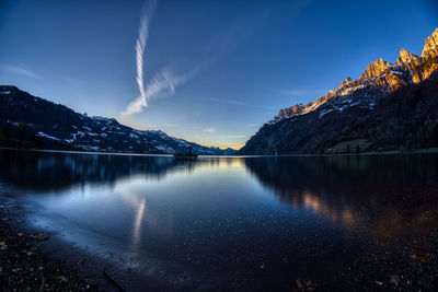 Scenic view of lake by snowcapped mountains against sky during winter