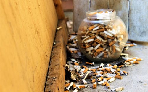 Burnt cigarettes in jar on footpath