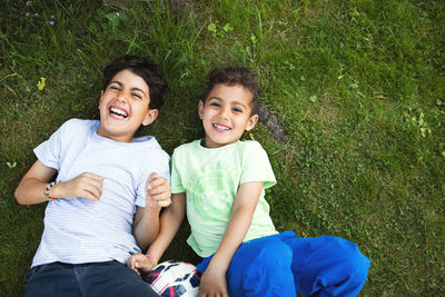 Directly above shot of happy boys lying on grassy field