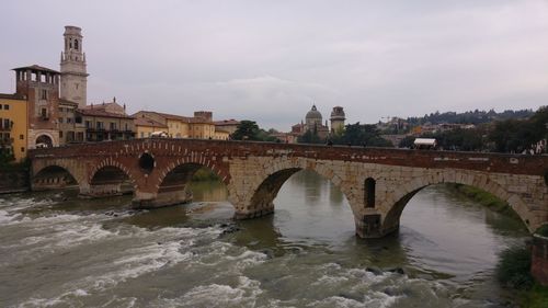 Arch bridge over river against buildings in city