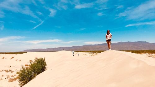 Woman standing on desert against sky