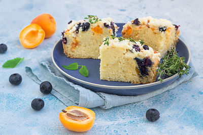 Slices of apricot and blueberry crumble cake decorated with thyme. 