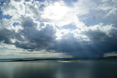 Sunlight streaming through clouds over sea