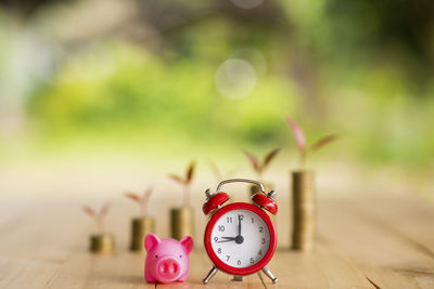 Alarm clock and piggy bank against coins on table