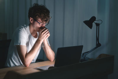 Young woman using mobile phone while sitting on table