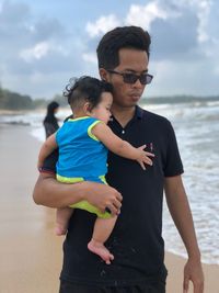 Father carrying baby boys at beach