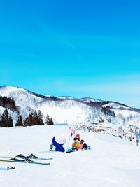 People skiing on snowcapped mountain against blue sky