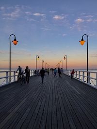 People at sea shore against sky during sunset