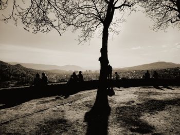 Silhouette people by lake against sky