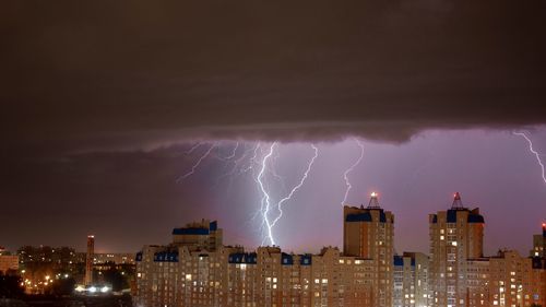 Lightning over illuminated buildings in city at night