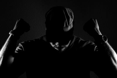 Muscular man wearing cap against wall in darkroom