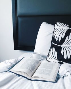 High angle view of book with cup and cushions on bed