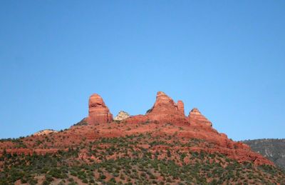 Low angle view of rock formations against clear blue sky