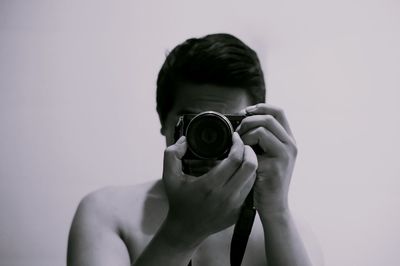 Portrait of man photographing against white background