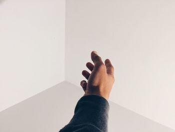 Close-up of cropped hand gesturing towards white wall