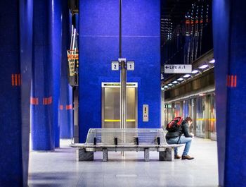 Side view of man standing on bench at subway platform