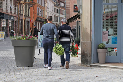 Rear view of people walking on street in city