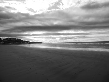 Scenic view of beach against cloudy sky