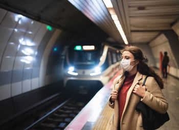 Woman wearing mask standing on railroad station platform