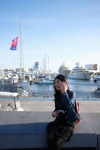 Woman sitting in harbor against sky