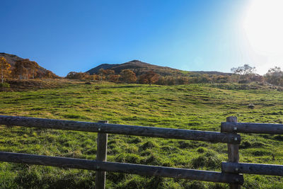 Fence on field by mountain against sky