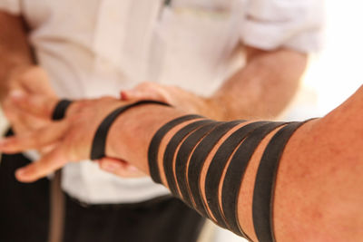 Midsection of man tying bandage on hand