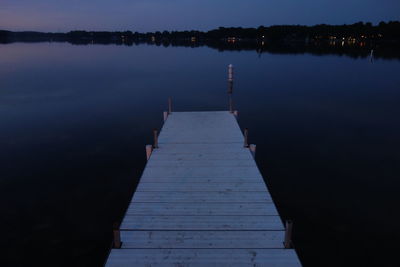 Pier over lake against sky at night