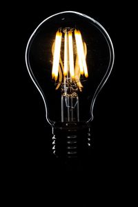 Close-up of illuminated light bulb against black background