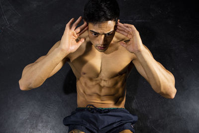 Shirtless muscular man exercising against wall