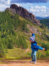 Full length of boy standing against rock mountain