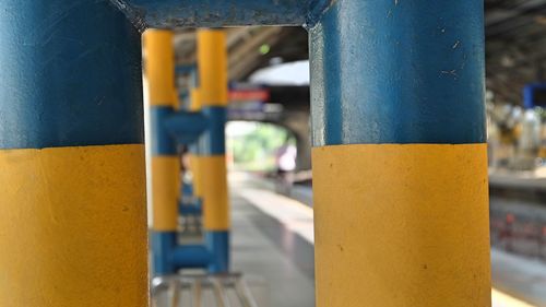 Close-up of yellow metal pole against wall