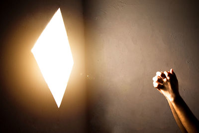 Close-up of praying hand holding illuminated light