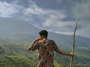 Rear view of woman looking at mountains against sky