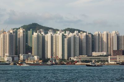 Sea by buildings against sky in city