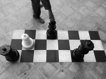 Cropped image of person holding chess piece over chess board on street