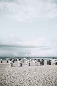 Hooded chairs on beach against sky