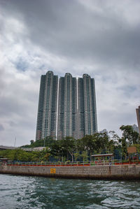 Modern buildings by river against sky in city