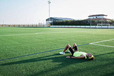 Young man rests on the grass of a soccer field after training