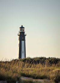Cape henry lighthouse on field against sky