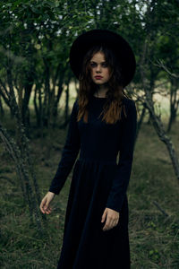 Portrait of young woman standing against plants