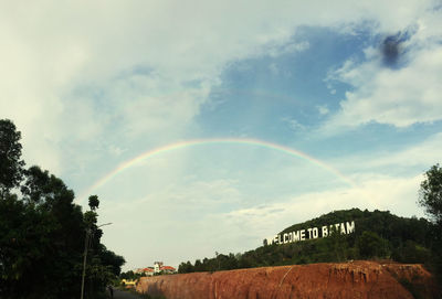 Scenic view of rainbow over trees against sky