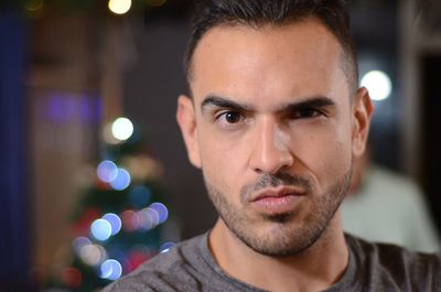 Close-up portrait of young man against illuminated lights