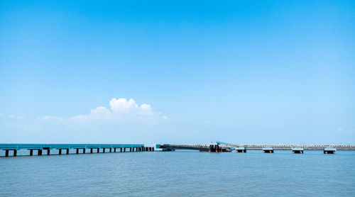 Bridge over calm blue sea against sky