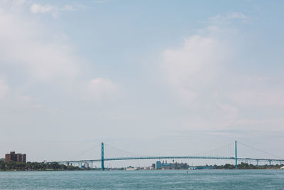 Bridge over river against cloudy sky