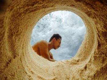 Side view of a man looking through hole