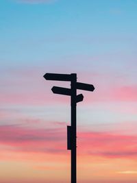 Silhouette cross on pole against sky during sunset